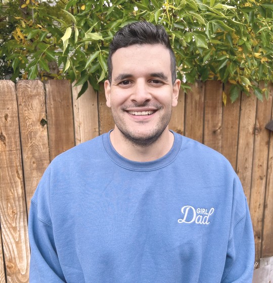 Simon smiling in a Girl Dad sweatshirt